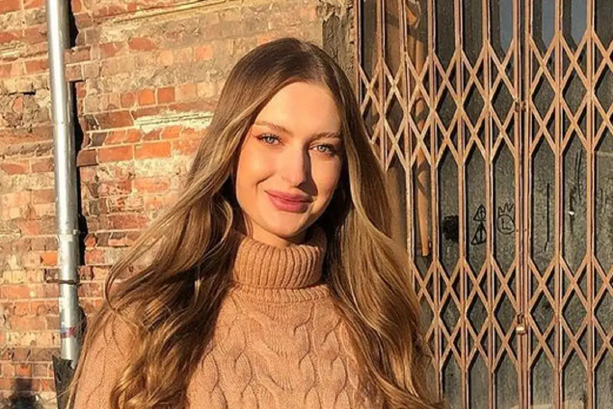 Uśmiechnięta Sophie, jak prawdziwa top model, pozuje na tle ceglanej ściany i metalowej kraty.