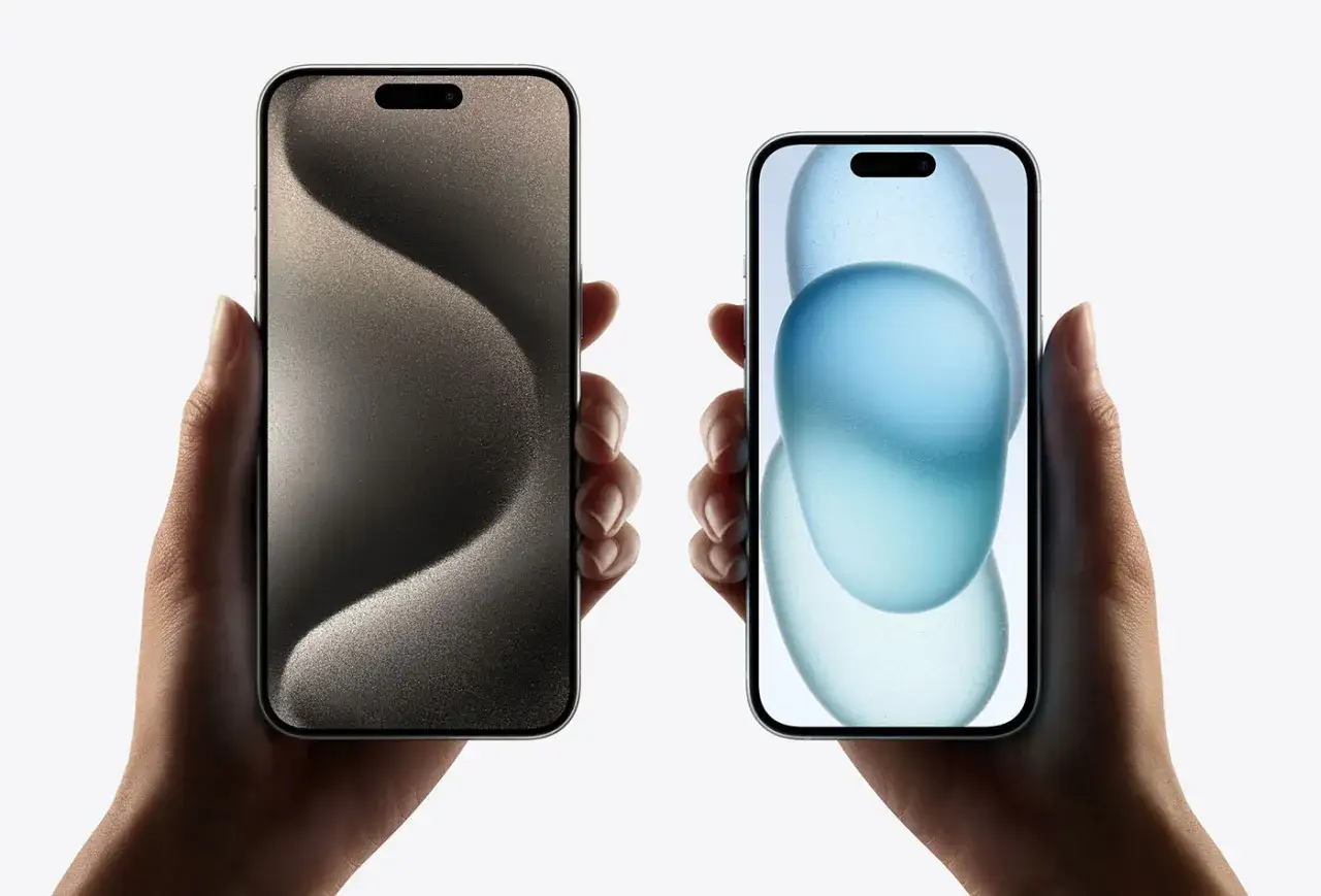 Dwie dłonie trzymają telefony. Po lewej ciemny ekran z falistym wzorem, po prawej jasny ekran z niebieskimi, p&oacute;łprzezroczystymi kształtami. To przyszły iPhone 18 Pro Max.