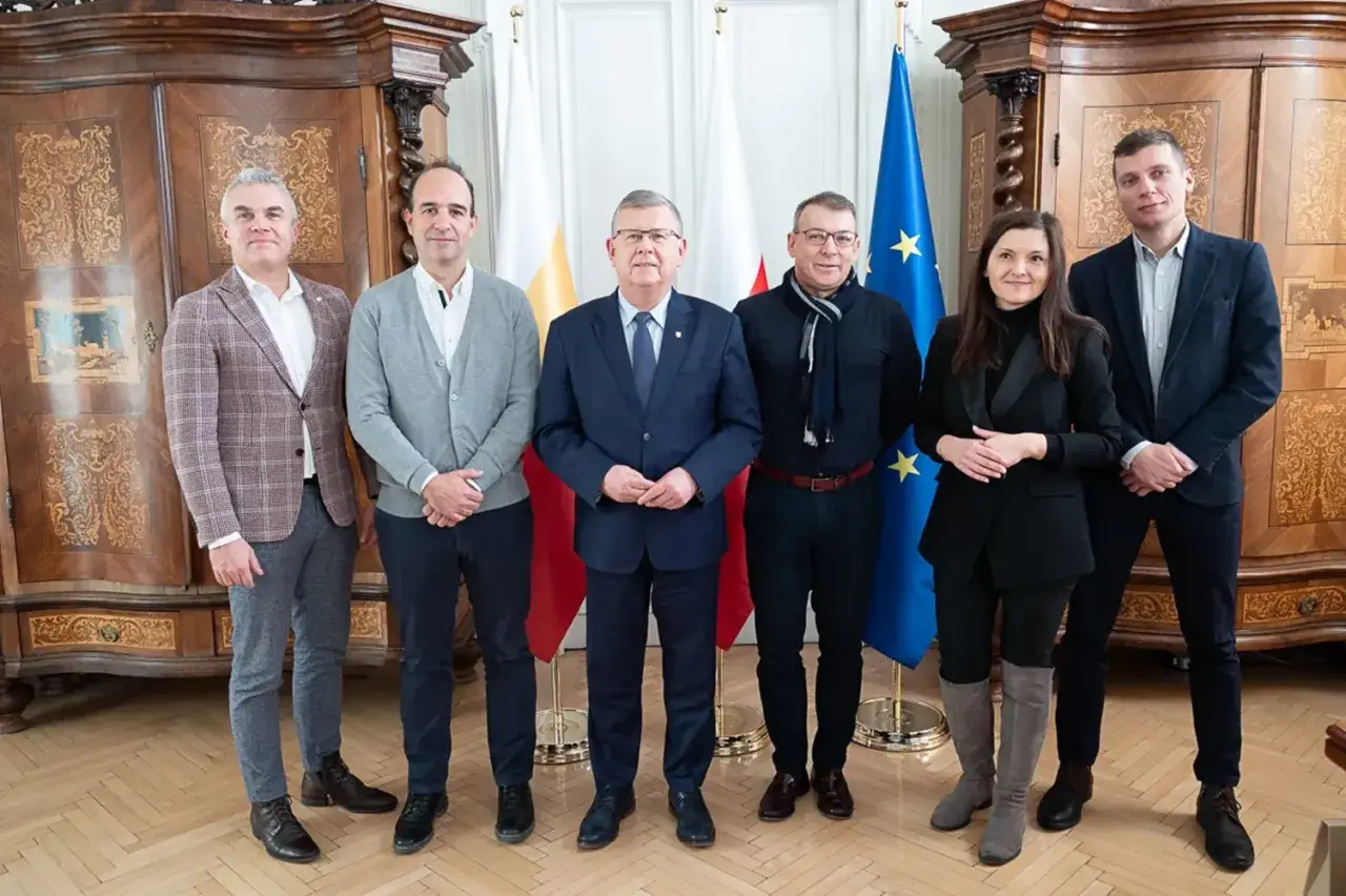 Grupa osób pozuje do zdjęcia przed flagami. Dyskutują, czy gmina ma osobowość prawną.