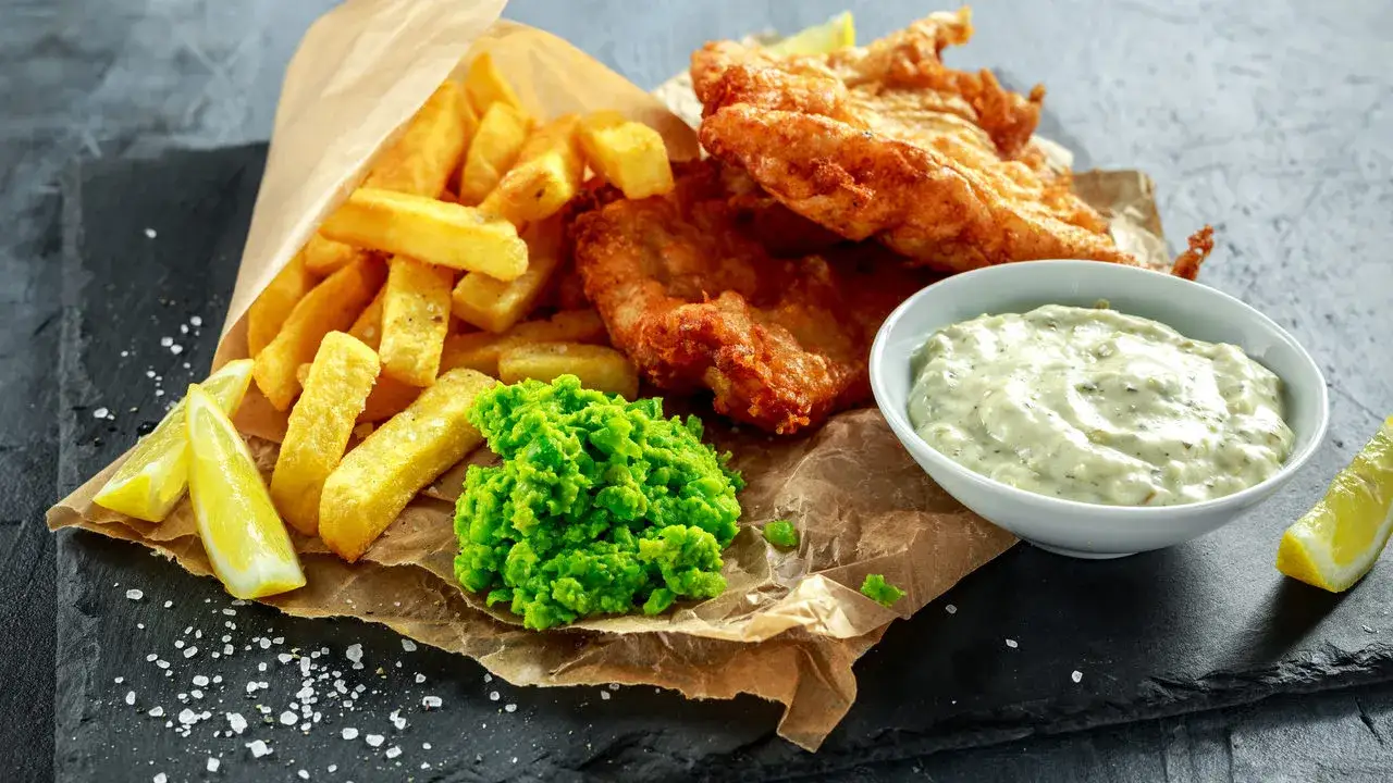smażona ryba z frytkami i sur&oacute;wką na talerzu w nadmorskiej restauracji