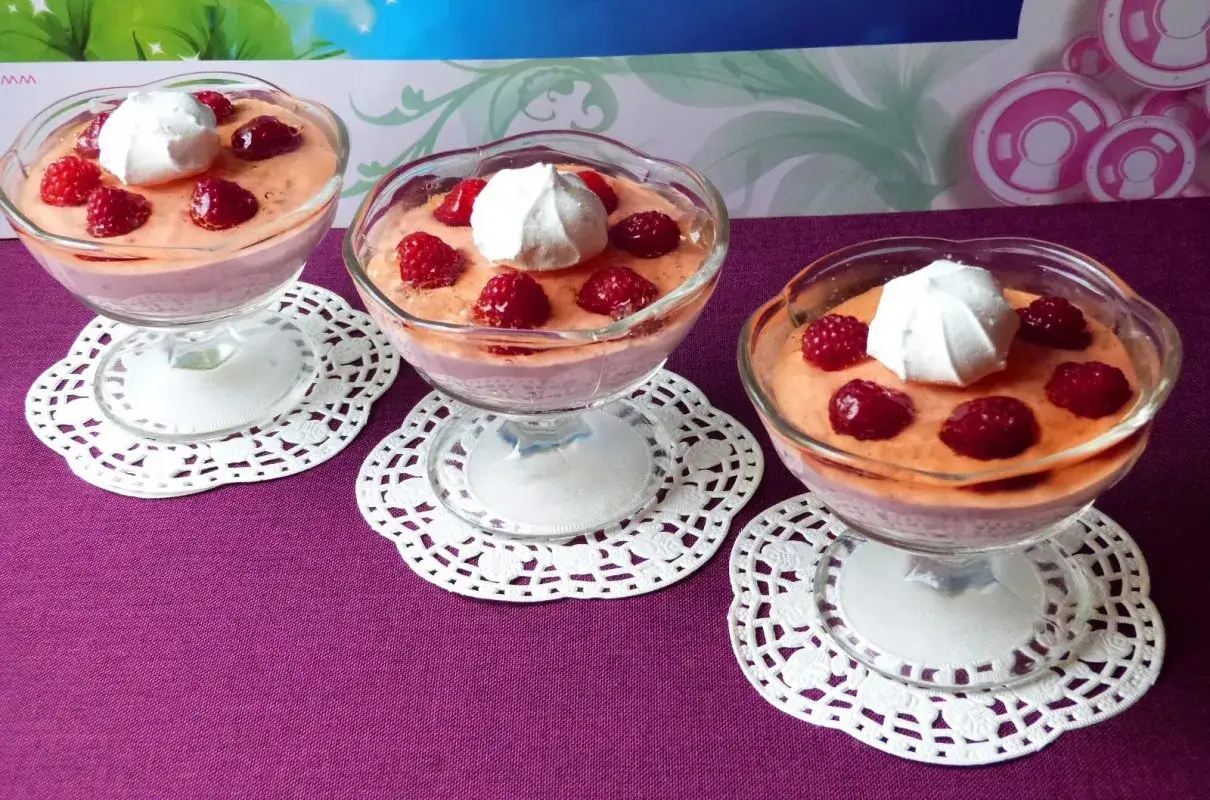 Pyszny deser z twarogiem, malinami i bitą śmietaną w pucharkach. Idealny na letnie popołudnie.