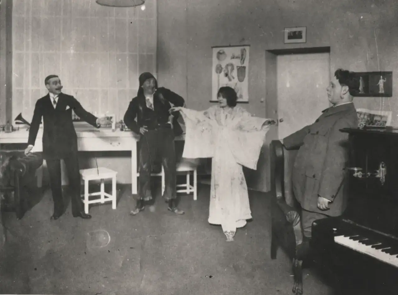 Szyfman, reżyser teatralny, kieruje pr&oacute;bą. Aktorzy w strojach z epoki, kobieta w zwiewnej sukni, mężczyzna w garniturze i w stroju ludowym.