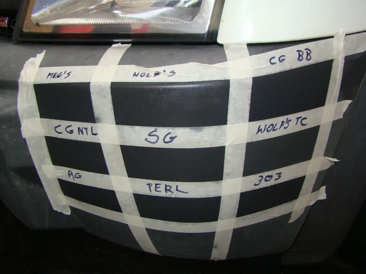 Testowanie różnych produktów czernidło do zderzaków na czarnym zderzaku, oznaczone taśmą.