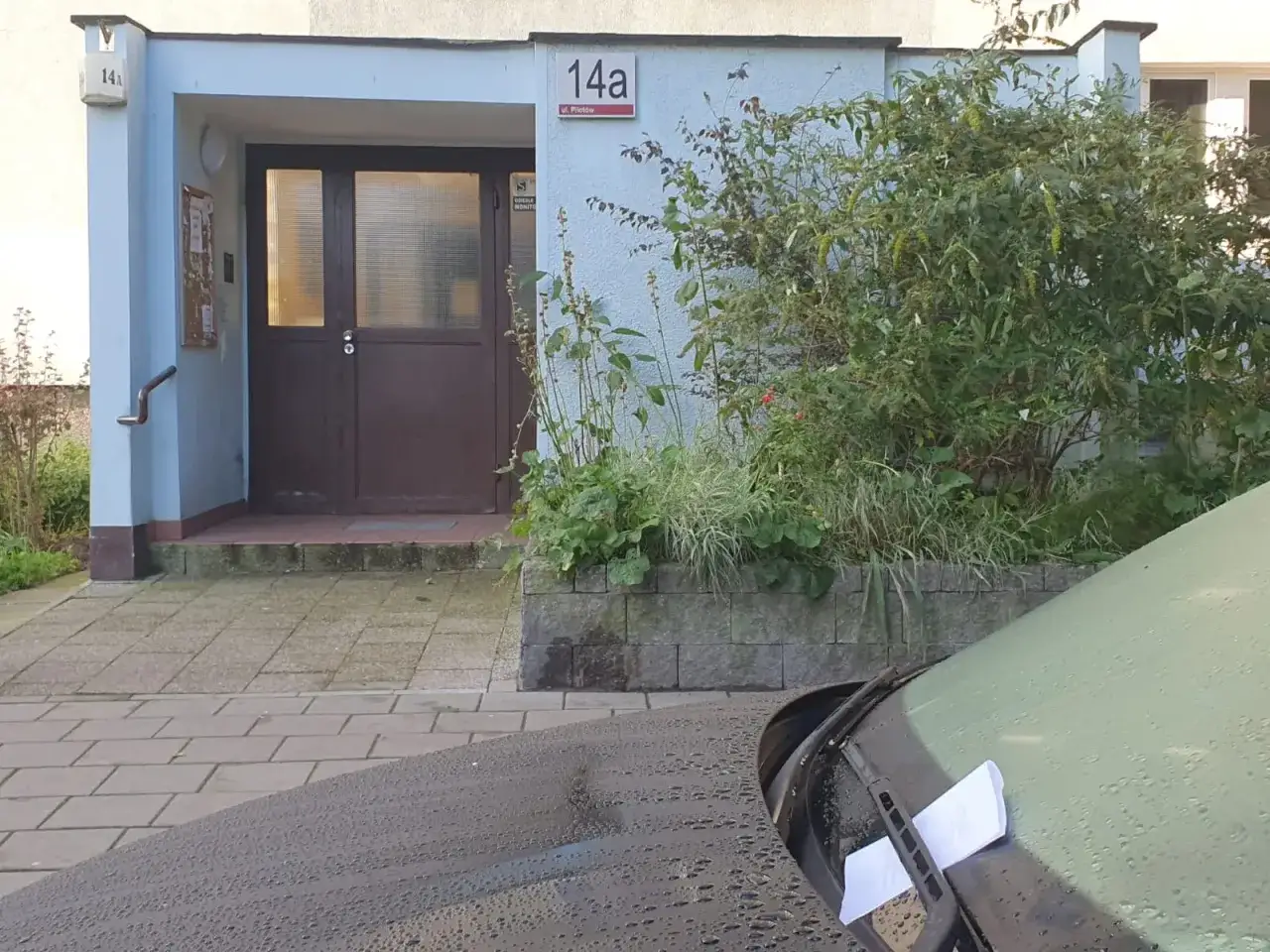 Mandat za parkowanie na terenie wspólnoty mieszkaniowej na ul. Pilotów 14a. Na szybie samochodu leżą białe kartki.