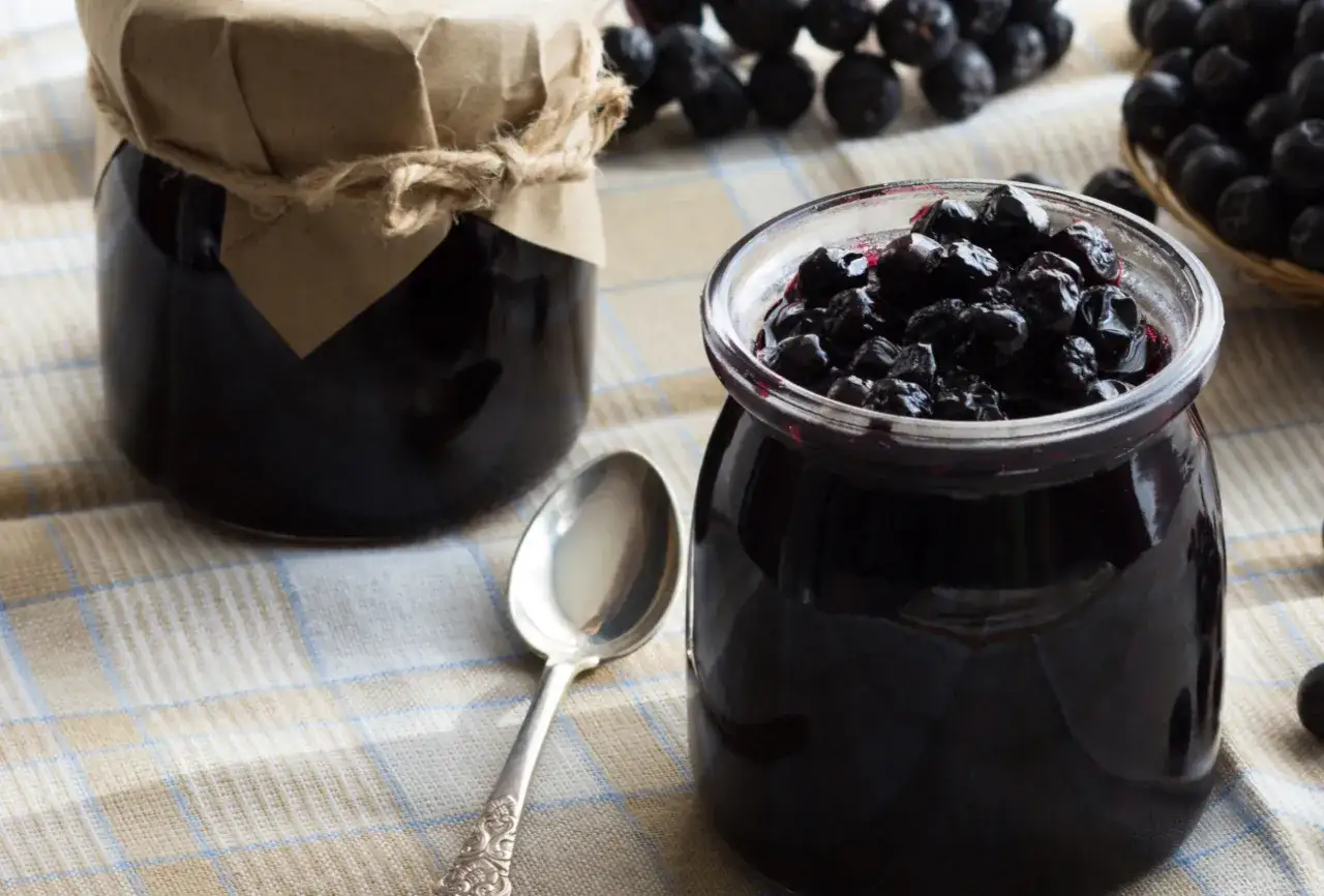 Słoiki z przetworami z aronii, gotowe do przechowywania. To świetny sposób, jak mrozić aronię, by cieszyć się jej smakiem przez cały rok.