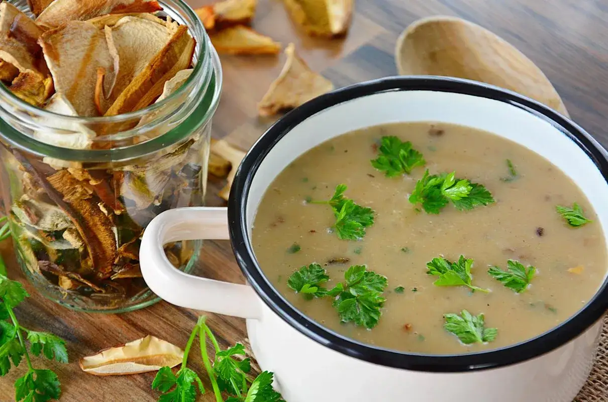 Aromatyczny sos grzybowy z suszonych grzyb&oacute;w, udekorowany natką pietruszki. Obok słoik pełen suszonych grzyb&oacute;w.