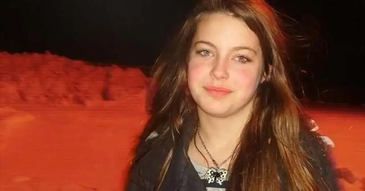 Izabela Strzałkowska z motylkiem na szyi, na tle pomarańczowego, zaśnieżonego krajobrazu.