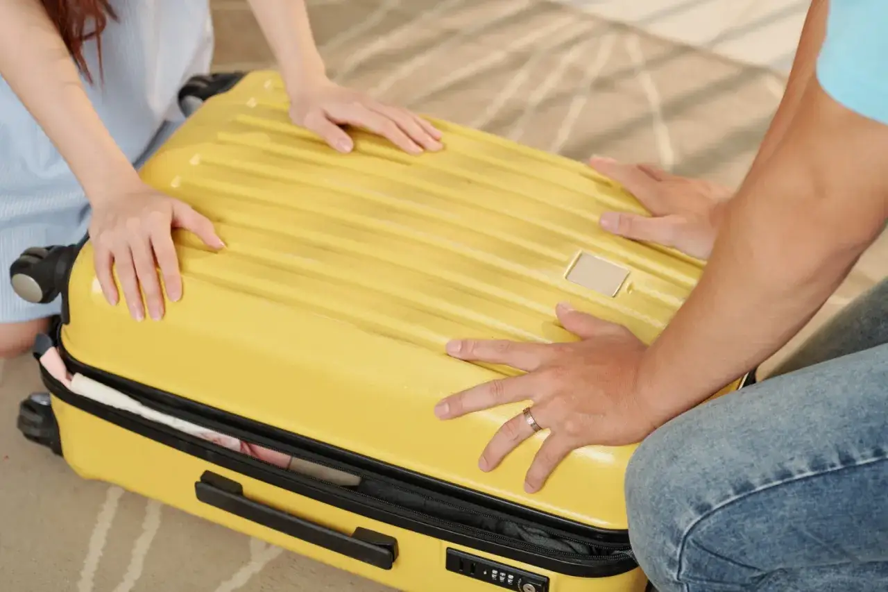 Przygotowujemy się do wyjazdu do sanatorium. Jak wysłać walizkę kurierem? Zamykamy żółtą walizkę, by wszystko dotarło bezpiecznie.