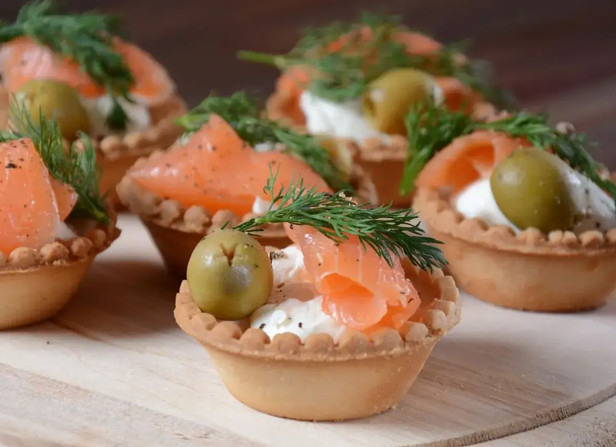 Pyszne przystawki na zimno: kruche babeczki z łososiem, serkiem, oliwką i koperkiem. Idealne na każdą okazję.
