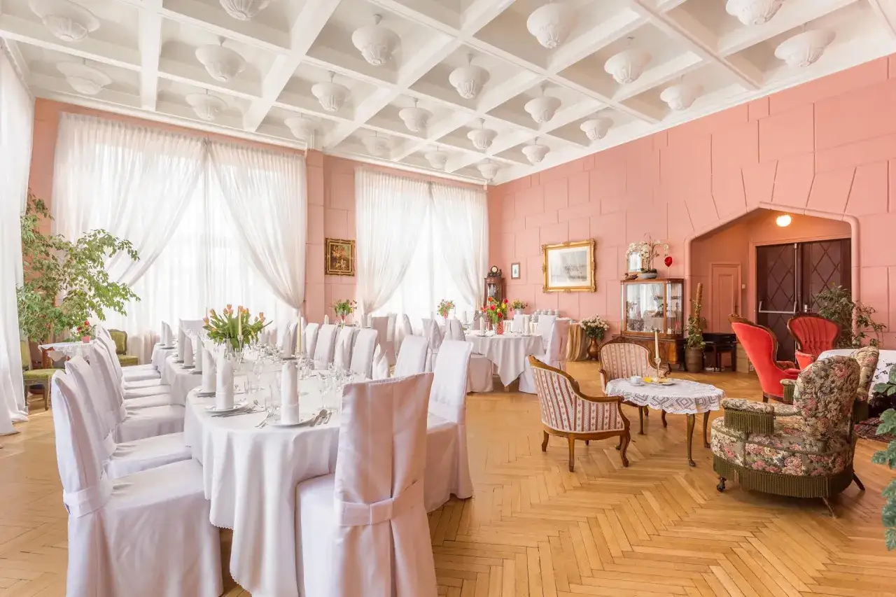 Elegancka sala bankietowa z białymi obrusami i krzesłami. Czy w teatrze można jeść? Tu tak, przygotowano stoły na przyjęcie.