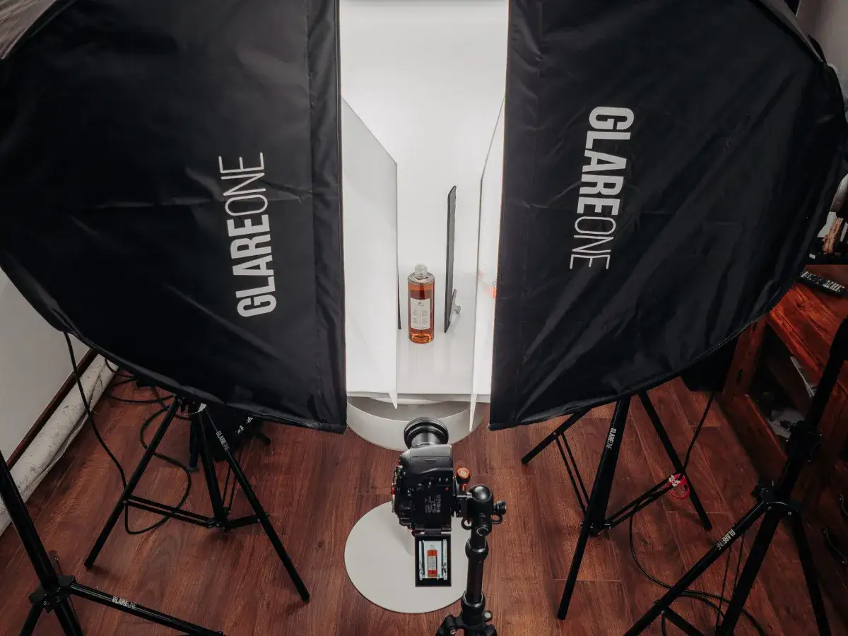 Profesjonalne ustawienie aparatu do fotografii produktowej. Dwa duże softboxy GlareOne oświetlają butelkę z płynem.