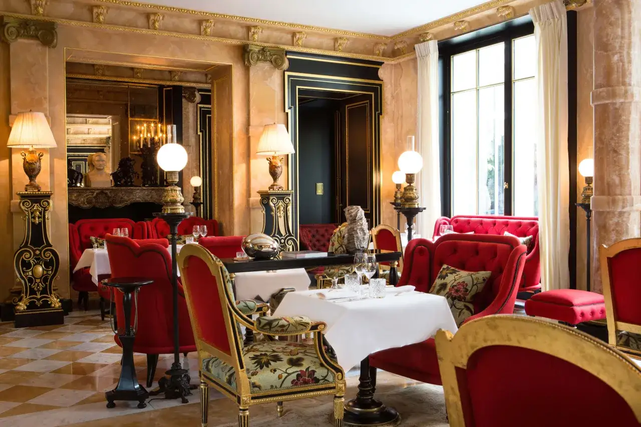 Elegancka restauracja w słynnym paryskim hotelu. Czerwone aksamitne fotele i złote zdobienia tworzą luksusową atmosferę.