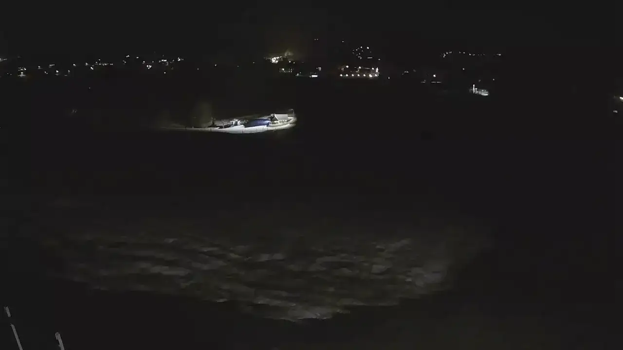 Nocny widok z olczański wierch kamery na ośnieżony teren i kilka budynków z oświetleniem.