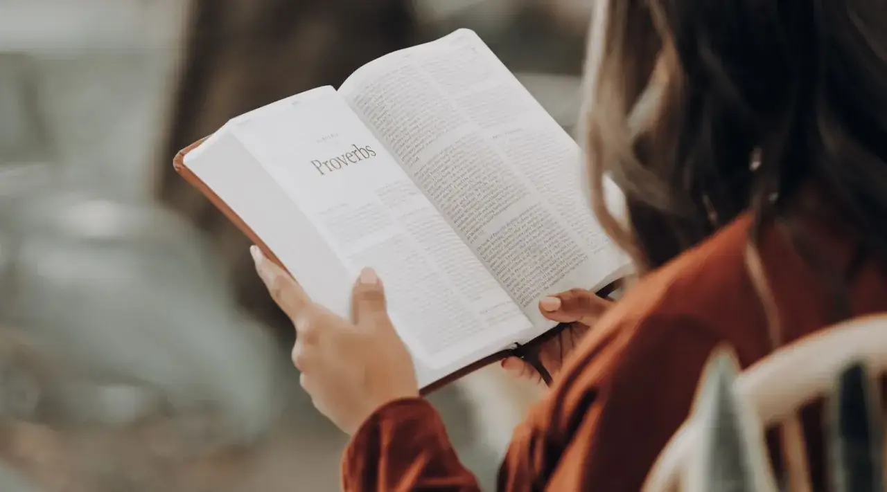 Kobieta czyta Biblię, szukając mądrości. To przykład biblioterapii dla dorosłych, gdzie słowa niosą ukojenie i wskaz&oacute;wki.