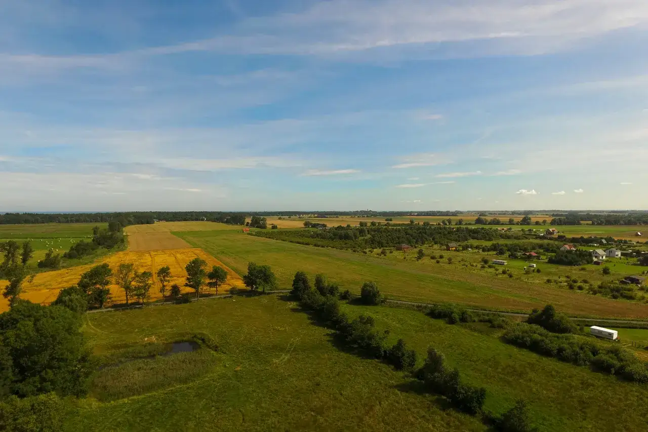 Rozległe pola i łąki, z domami w oddali. Taka działka inwestycyjna co to znaczy? To przyszłość, potencjał i spok&oacute;j.