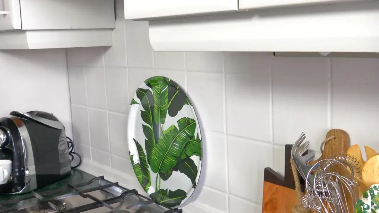 Jak odświeżyć płytki w kuchni? Dodaj kolorowy talerz z liśćmi bananowca na tle białych kafelków.