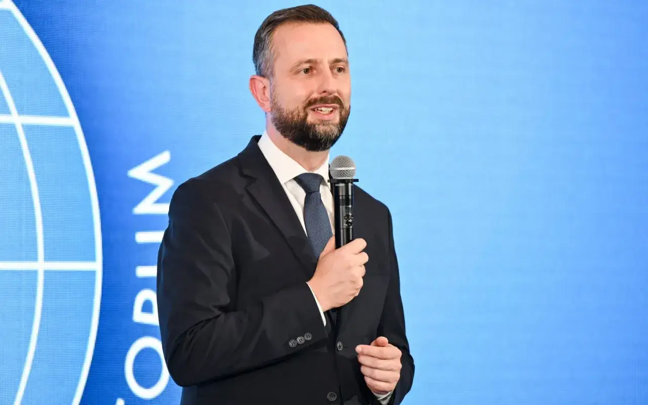 Władysław Kosiniak-Kamysz z mikrofonem, w garniturze, na tle niebieskiego ekranu z logo. Czyżby to początek nowego romansu z polityką?