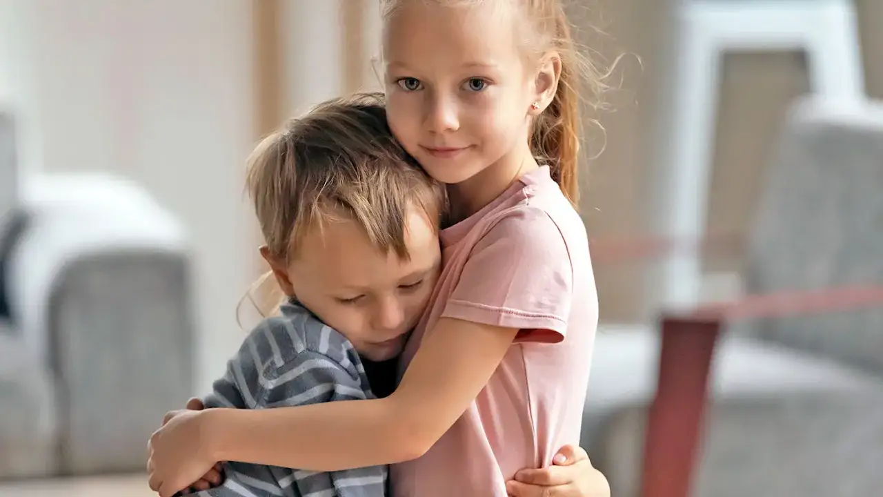 Starsza siostra pociesza młodszego brata, który może odczuwać fobia szkolna objawy.