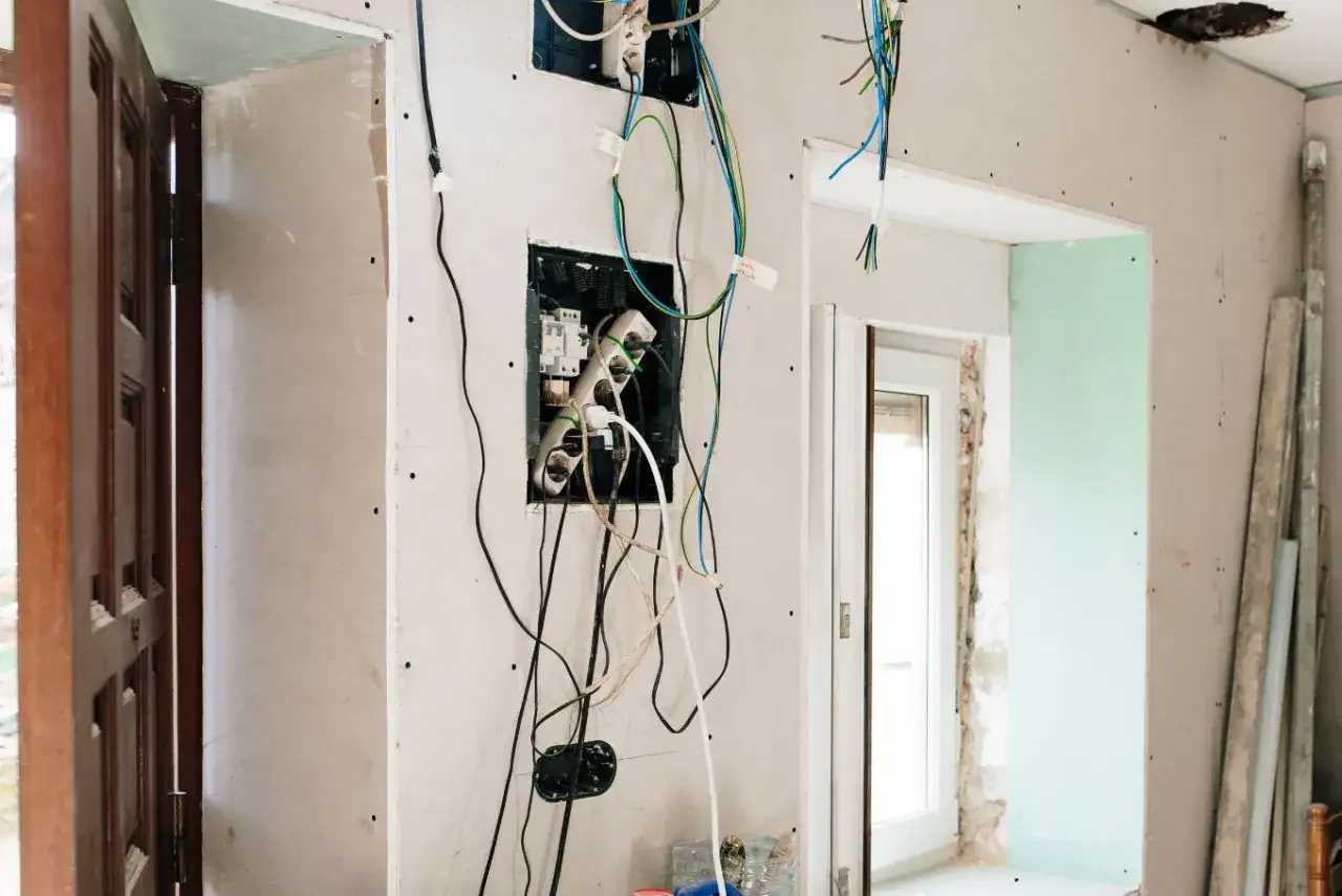 Przewody elektryczne wiszą luźno, czekając na podłączenie. Widać skrzynkę z bezpiecznikami i przygotowanie pod uziemienie w gniazdku.