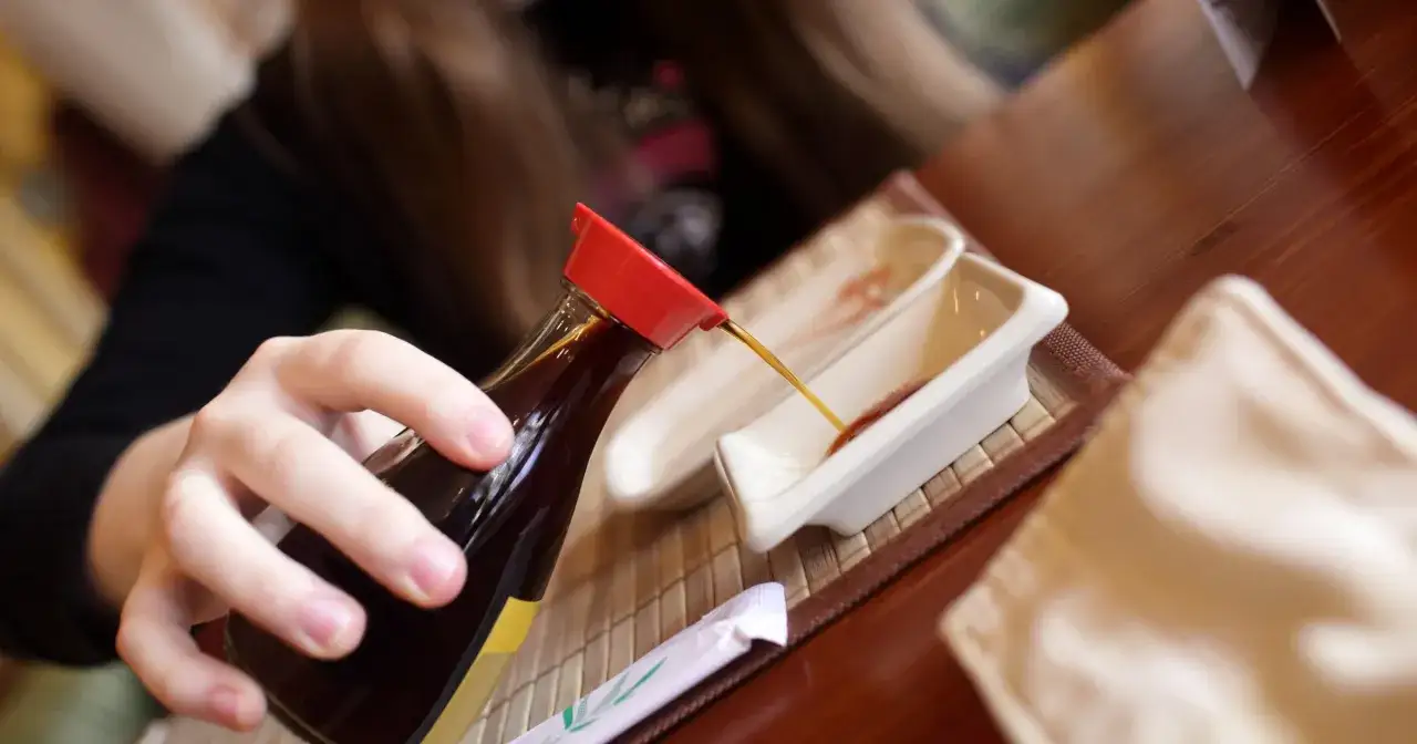 Butelki sosu sojowego na drewnianym tle z miseczkami do maczania