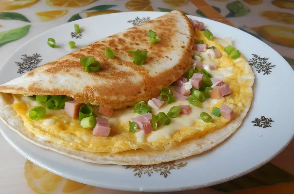 Pyszny omlet z tortillą, jajecznicą, szynką, serem i szczypiorkiem. Idealny na szybkie śniadanie.