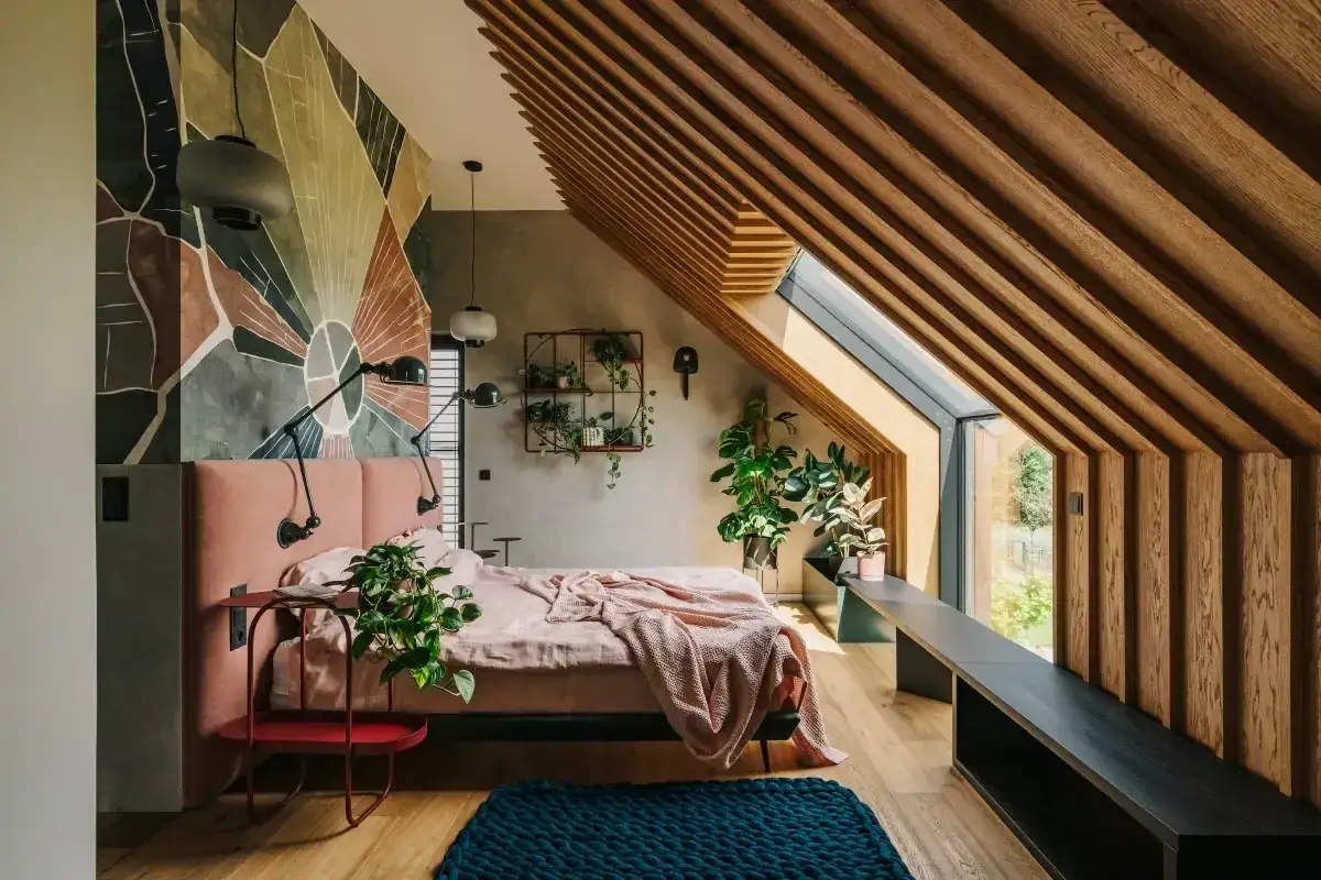 Mały pokój ze skosem aranżacje: różowa, tapicerowana rama łóżka, geometryczna tapeta, drewniane belki na suficie i duża, skośna okno.