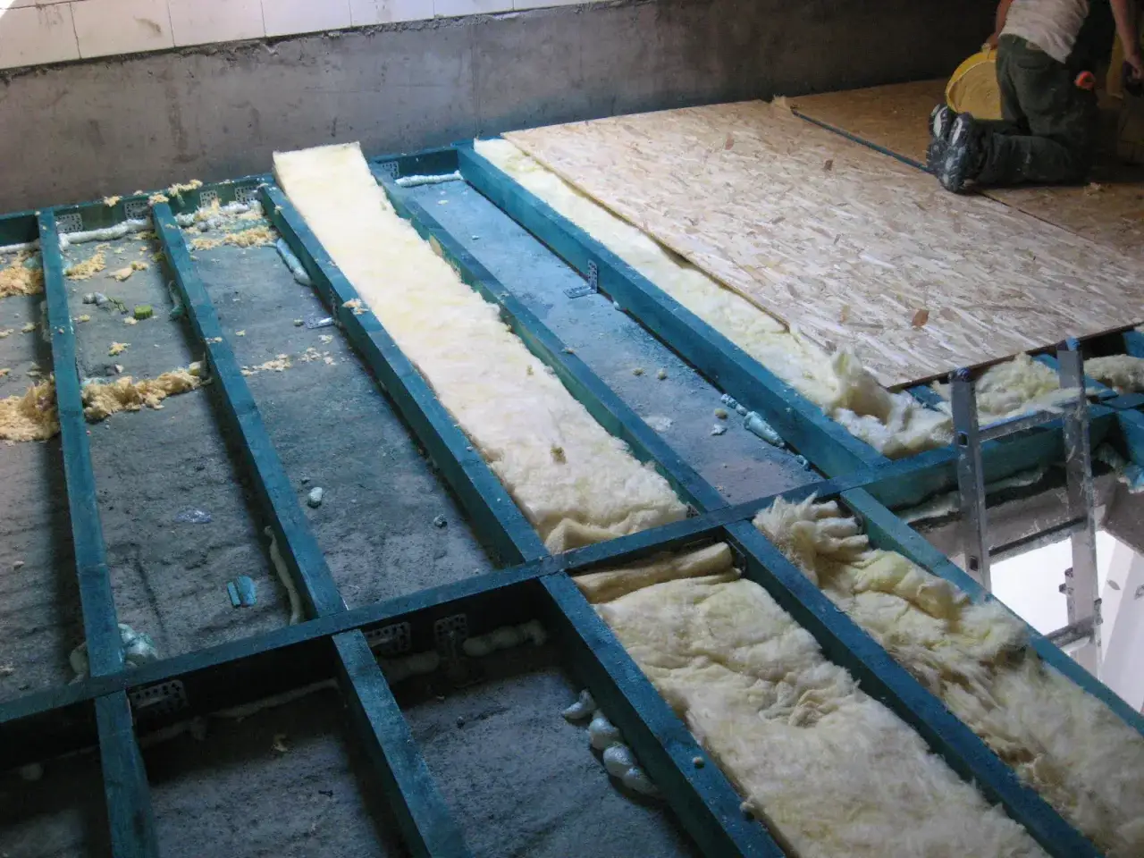 Budowa podłogi na legarach z wełną mineralną i płytami OSB.