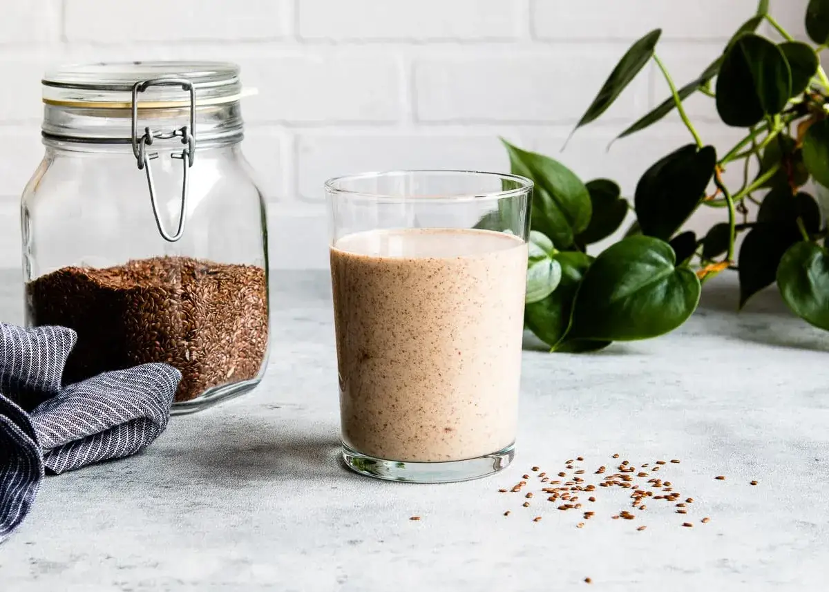 Słoik z siemieniem lnianym i szklanka napoju. Dowiedz się, jak przygotować siemię lniane do picia, by cieszyć się jego dobrodziejstwami.