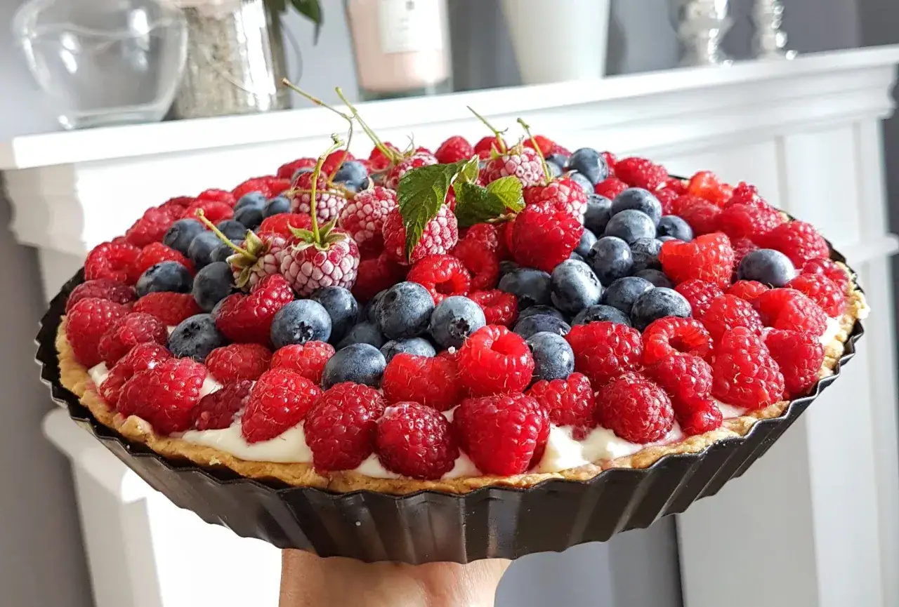 Pyszna tarta z truskawkami i bor&oacute;wkami, ozdobiona listkami mięty. Idealna na letnie popołudnie.