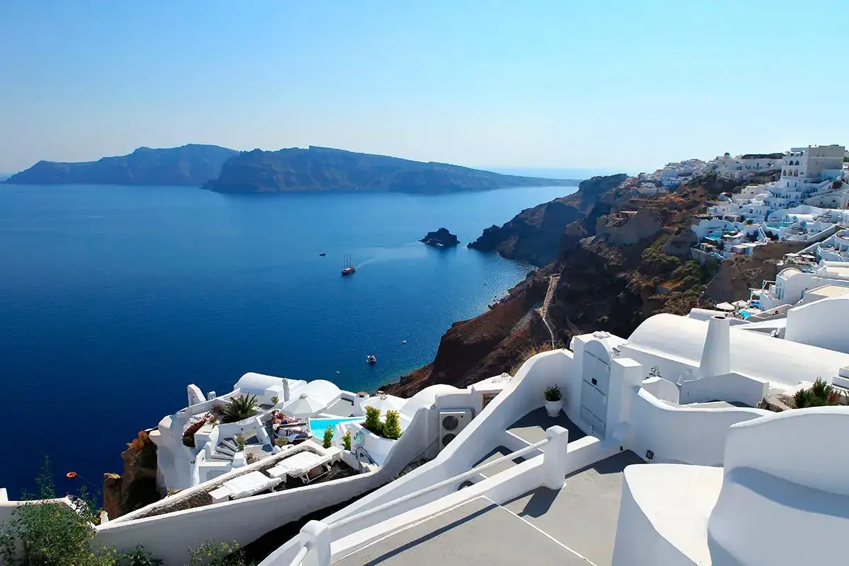 Widok na białe domy Santorini i błękitne morze. Krajobraz jak po trzęsieniu ziemi, ale wciąż piękny.
