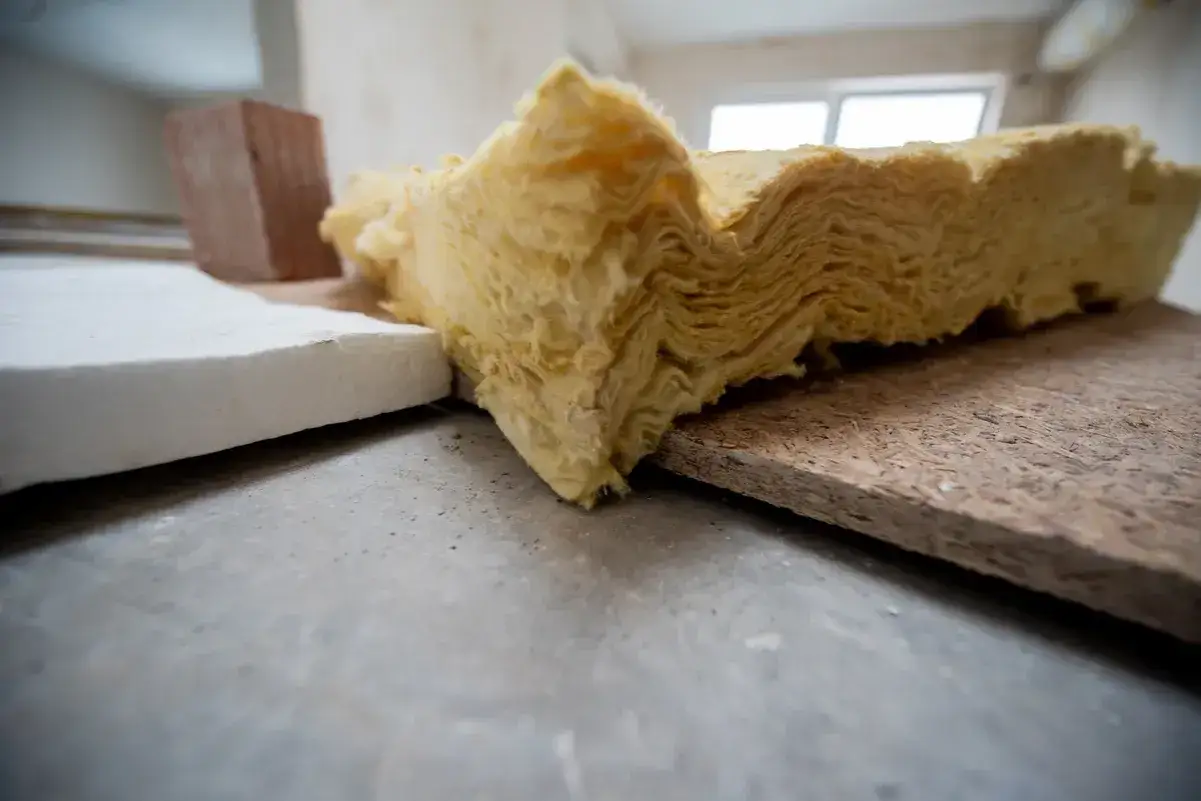 Na budowie widać materiały izolacyjne: białą płytę, cegłę i ż&oacute;łtą wełnę mineralną. Piana pur czy wełna &ndash; wyb&oacute;r należy do Ciebie.