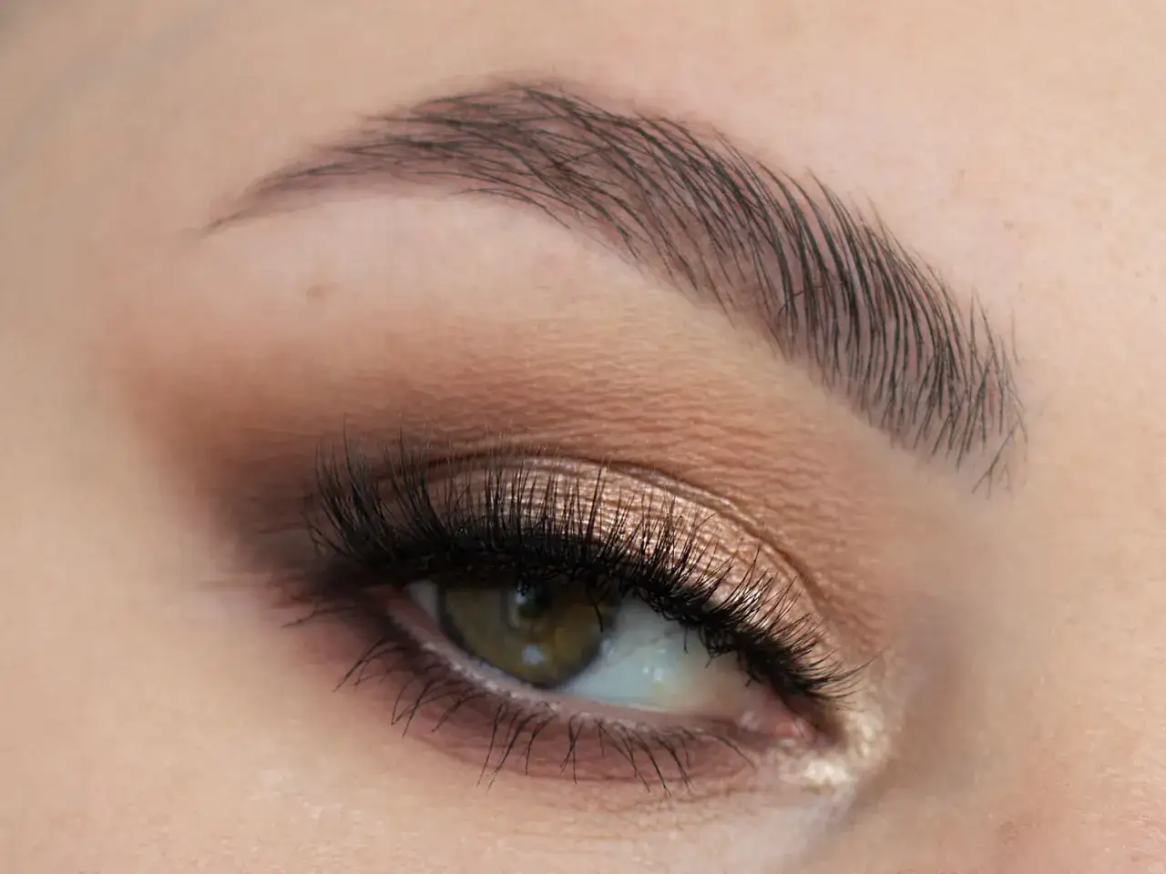 Elegancki makijaż na wesele: złociste cienie, wytuszowane rzęsy i podkreślone brwi.