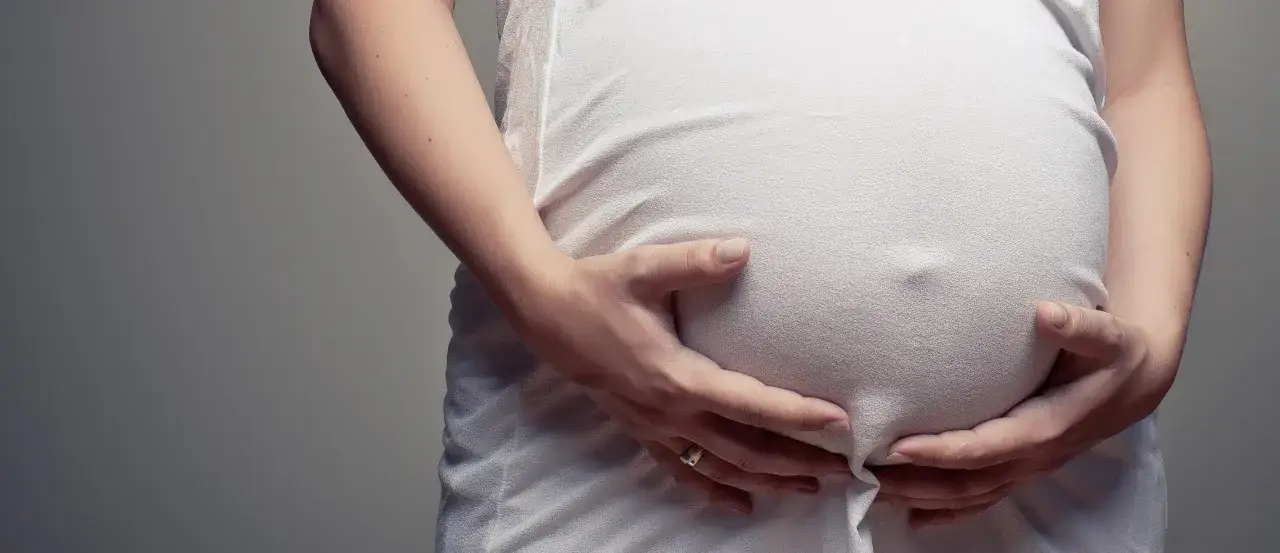 kobieta w ciąży trzymająca brzuch