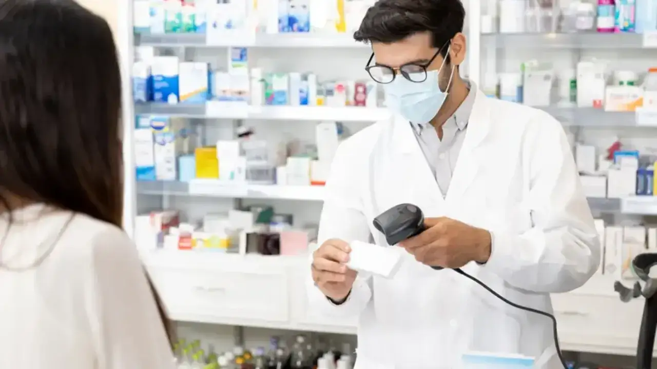 Farmaceuta skanuje lek, gdy klientka pyta, czy kupowanie leków przez internet jest karalne.