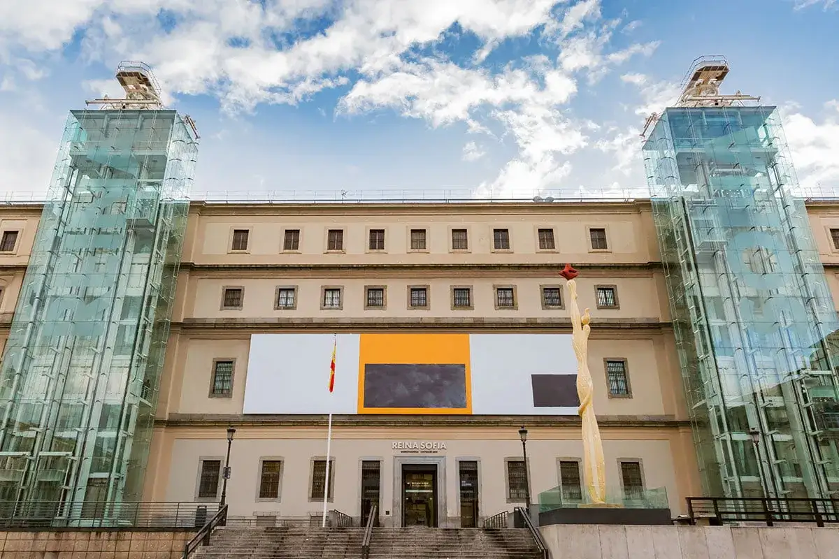 Muzeum Narodowe Centrum Sztuki Królowej Zofii w Madrycie, z nowoczesnymi szklanymi windami i rzeźbą.