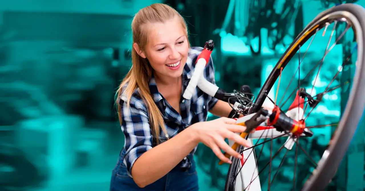 Uśmiechnięta dziewczyna majstruje przy rowerze, regulując stery.
