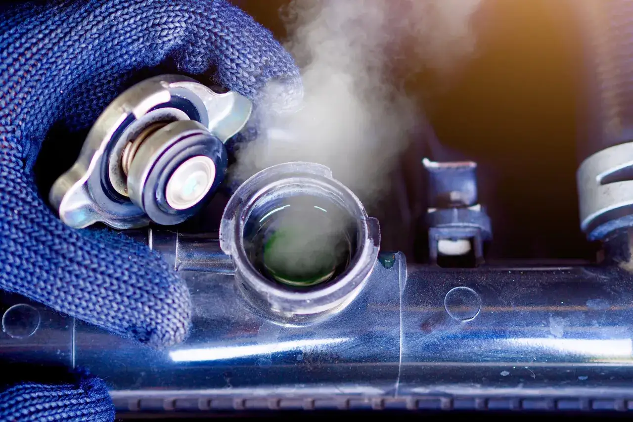 Para sprawdzić, czy można mieszać płyn chłodniczy, mechanik zdejmuje korek chłodnicy, z której wydobywa się para.