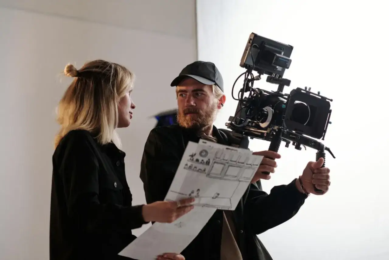 Nikodem Chabior z kamerą i storyboardem omawia ujęcie z asystentką.