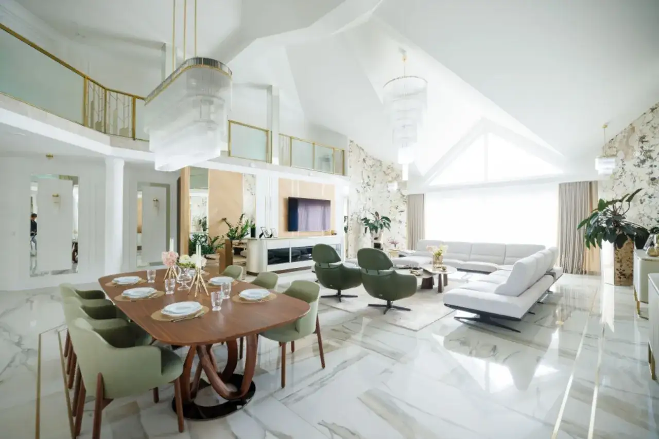 Elegancka jadalnia i salon w stylu country glam, z drewnianym stołem, zielonymi fotelami i białymi sofami.