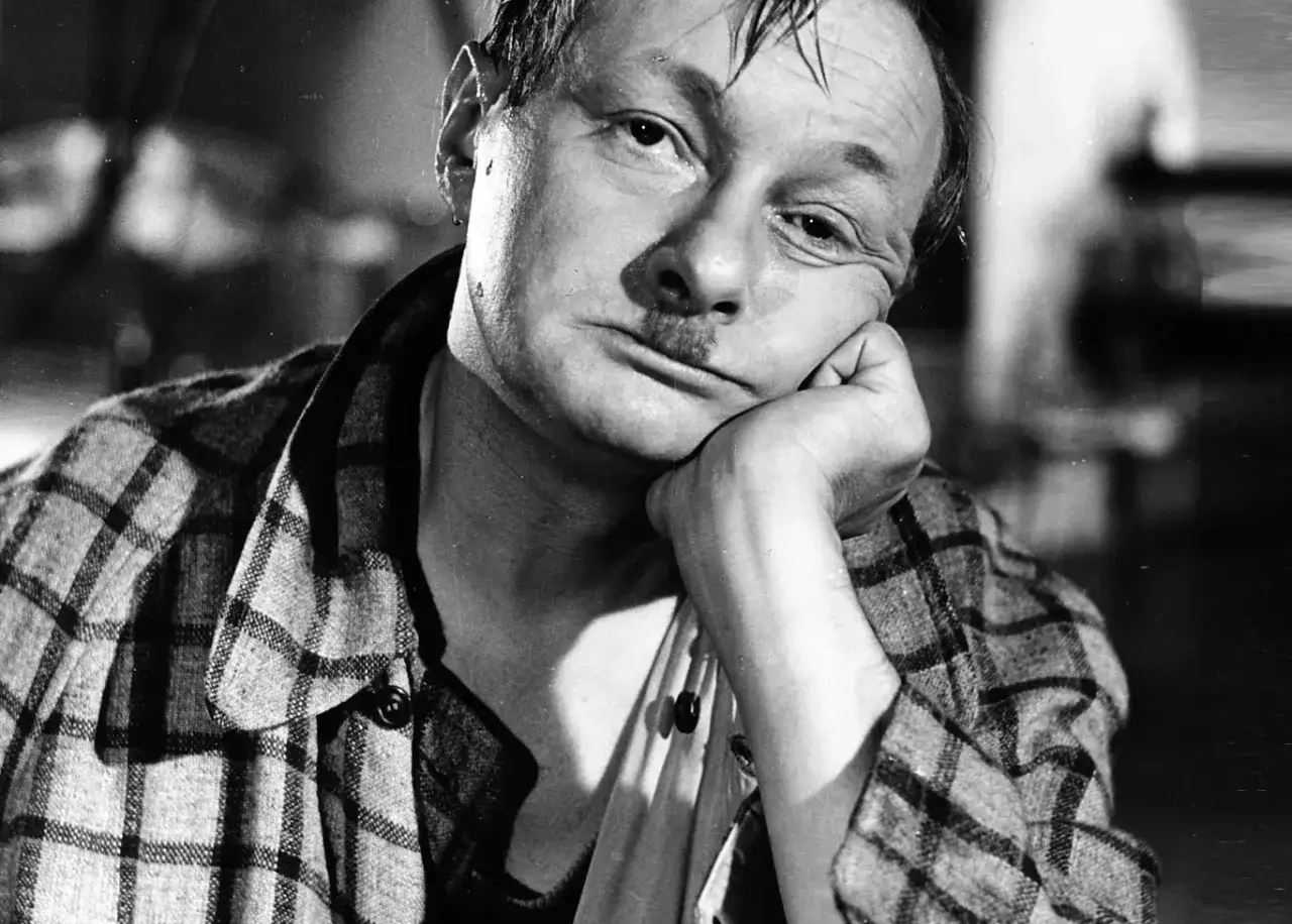 Tadeusz Fijewski w kadrze z jednego z jego filmów, zamyślony, opiera głowę na dłoni.