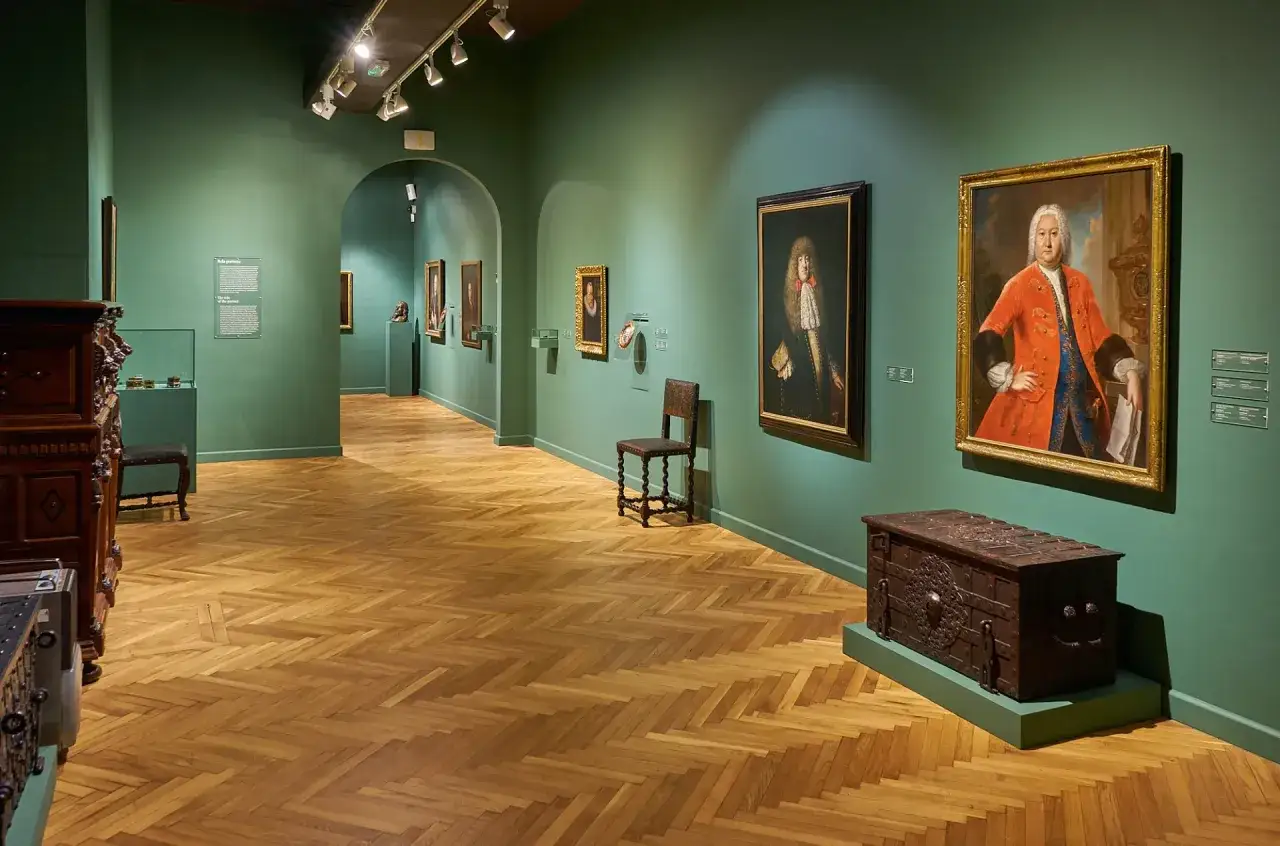 Wnętrze Muzeum Narodowego w Gdańsku z portretami i skrzynią.
