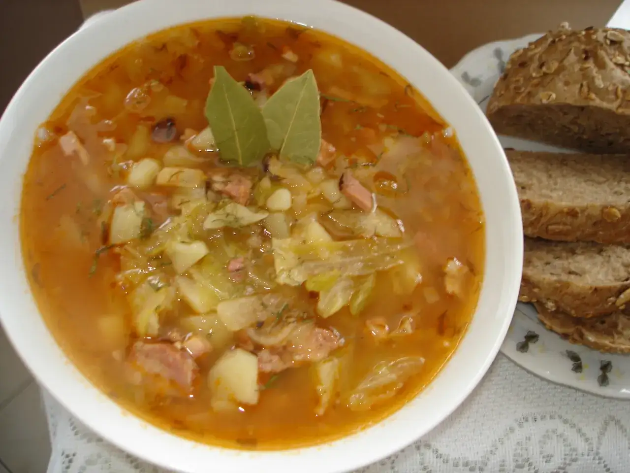 Aromatyczny kapuśniak ze słodkiej kapusty, z ziemniakami i kawałkami mięsa, podany z chlebem.