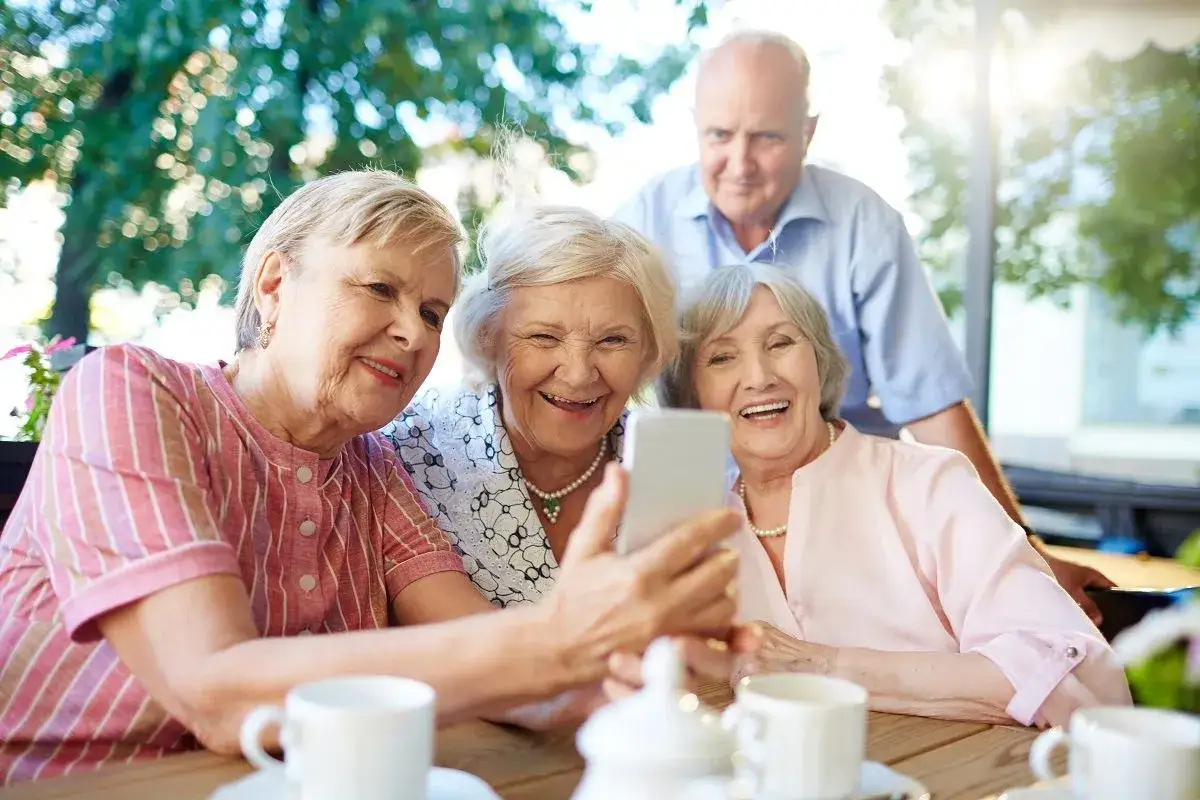 Uśmiechnięci seniorzy robią sobie selfie. Widać, że co to senior to radość życia i wsp&oacute;lne chwile.