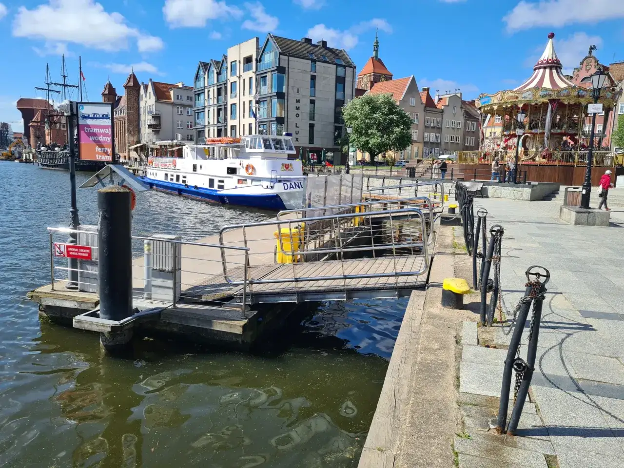 Widok na Motławę w Gdańsku, z tramwajem wodnym i karuzelą. Czy Gdańsk jest nad morzem? Tak, to miasto portowe nad Bałtykiem.