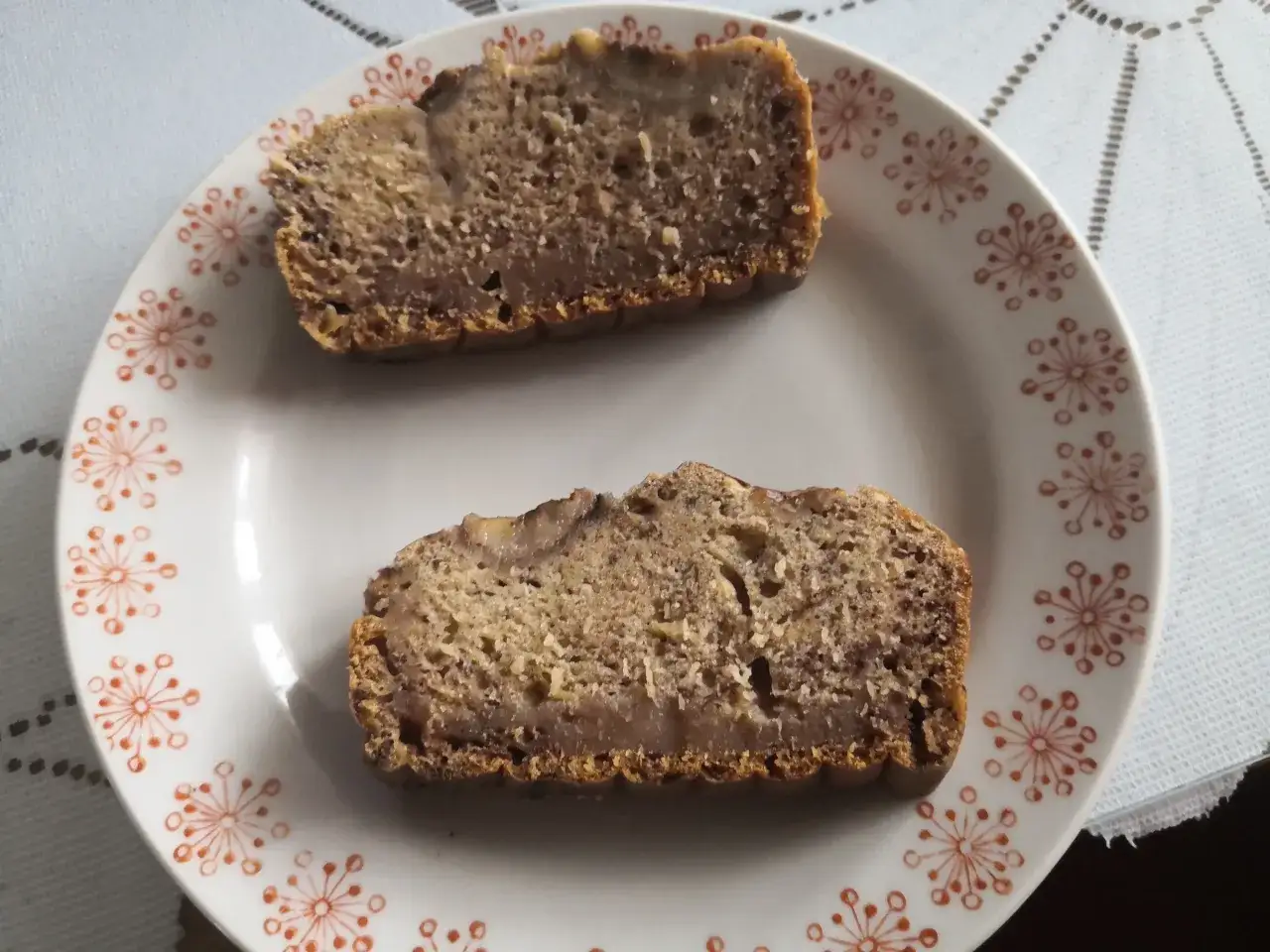 Dwa kawałki zakalca z chlebka bananowego na talerzu z pomarańczowymi wzorami. Zastanawiasz się, dlaczego chlebek bananowy wychodzi zakalec?