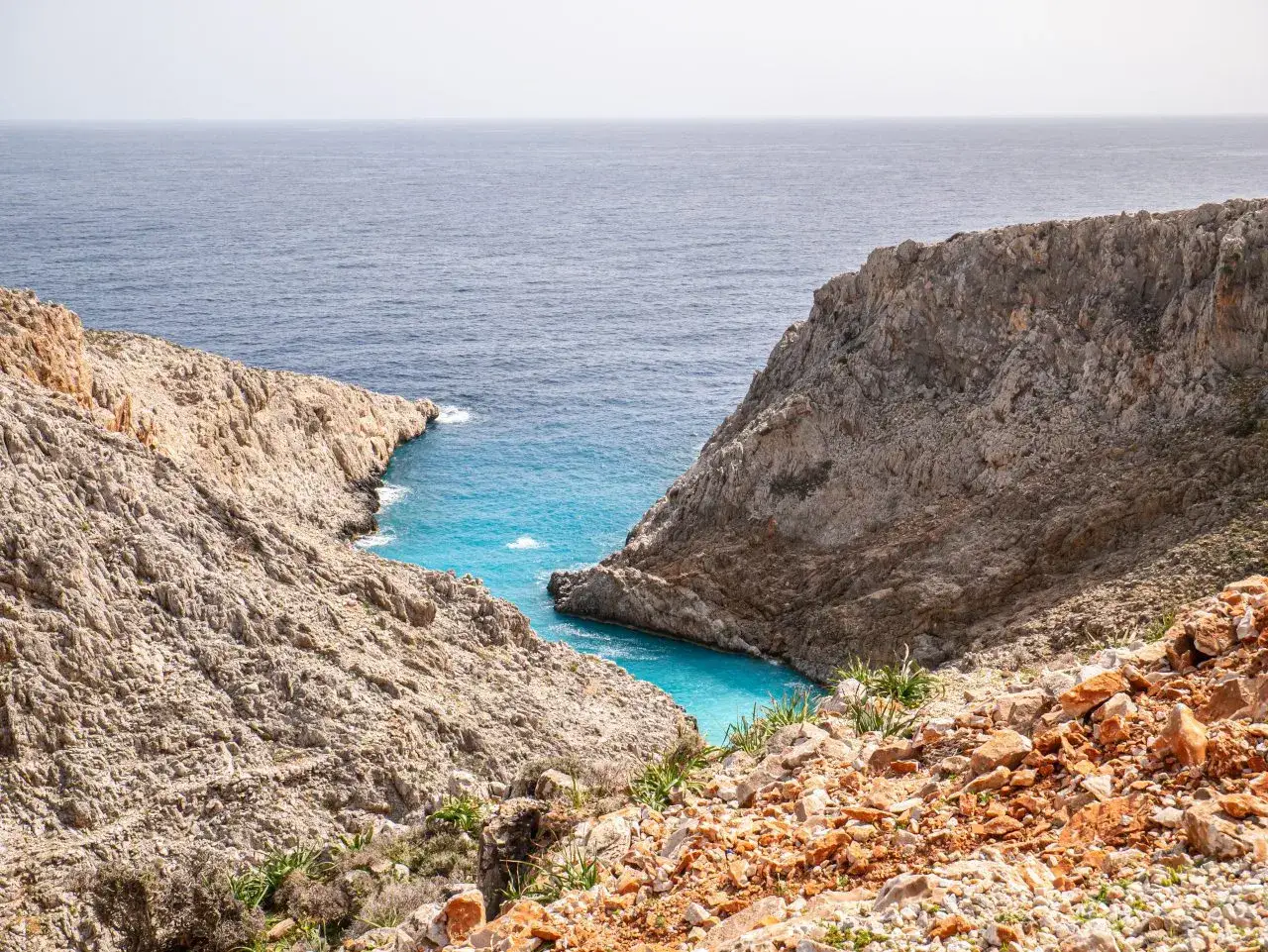 Majestatyczna zatoka na Krecie, otoczona skalistymi klifami. Turkusowa woda kusi do kąpieli w słoneczny majowy dzień.