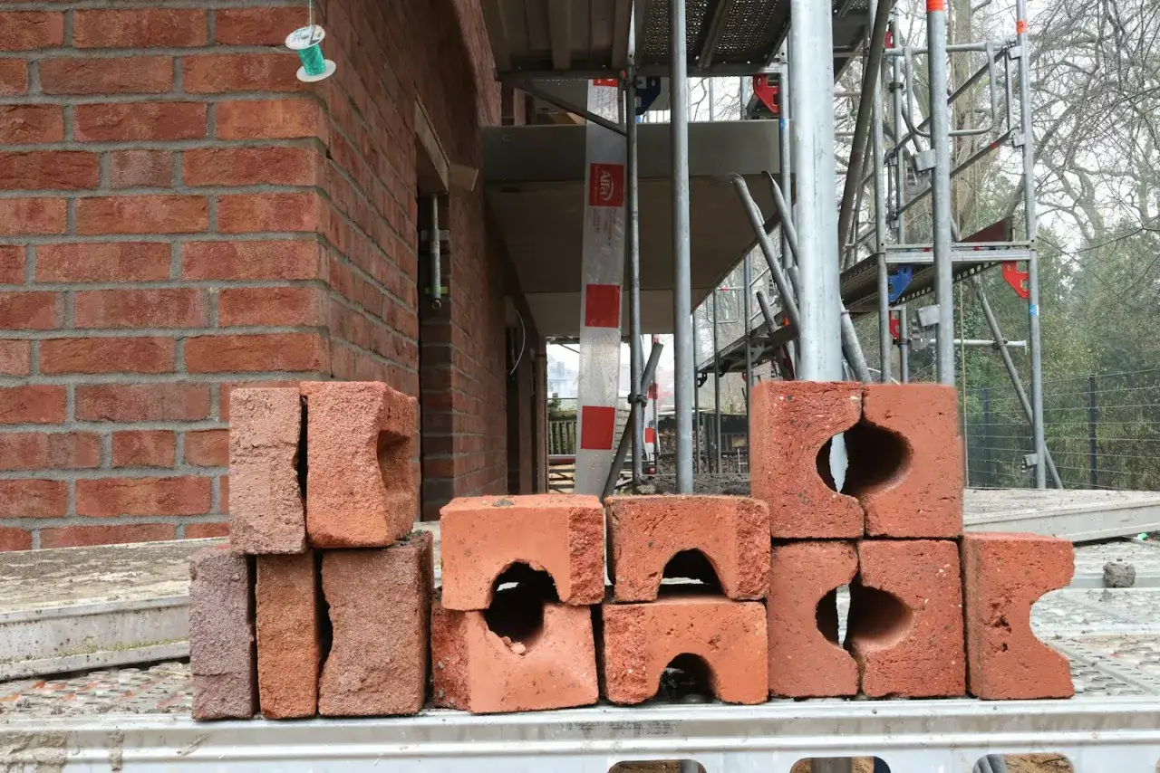 Stos cegieł, część obiektu budowlanego w budowie, z rusztowaniem w tle.