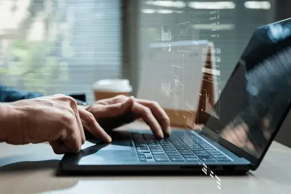 osoba analizująca wykresy giełdowe, uśmiechnięta, z laptopem