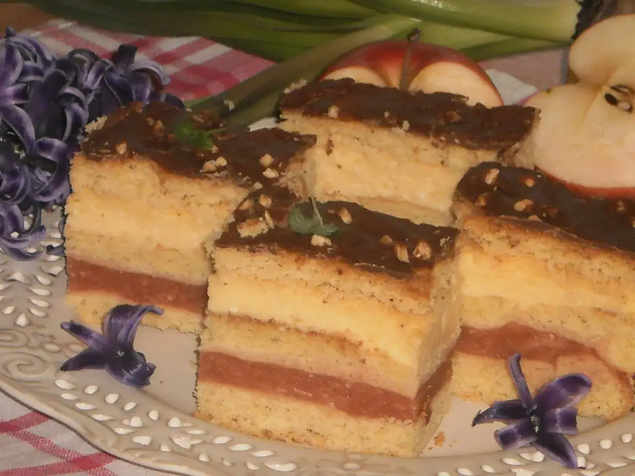 Pyszny przepis na ciasto delicja z serem i jabłkami. Warstwy biszkoptu, kremu serowego i jabłek, polane czekoladą.