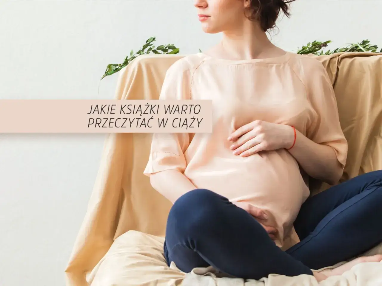 Przyszła mama z brzuszkiem, otoczona delikatnymi tkaninami, szuka inspiracji w książkach dla przyszłych mam.